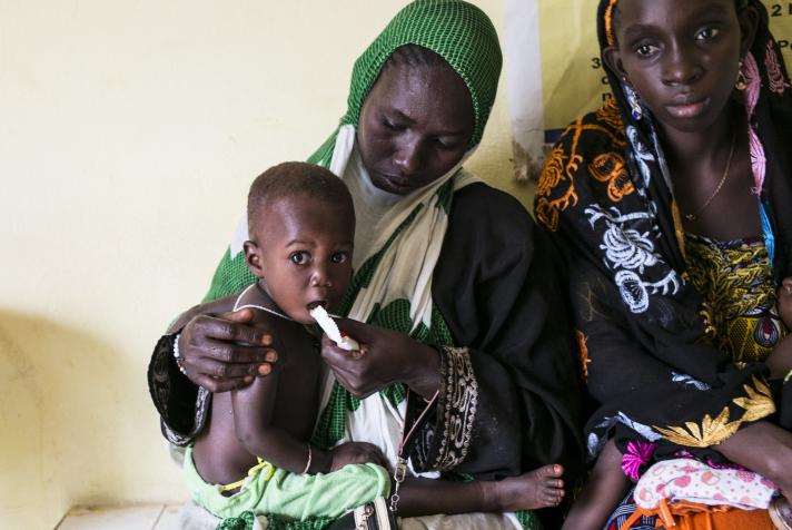 Hassin giving a dose of therapeutic food to her 1 year old daughter.