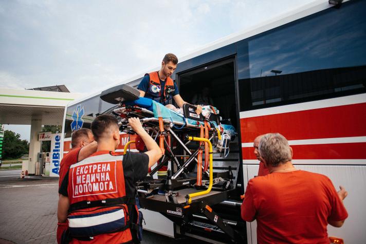 A patient on a stretcher being carrie into the ambulance bus.