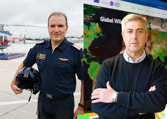 Man on the left in pilot's uniform in front of a helicopter and man on the right standing in front of large screens with maps
