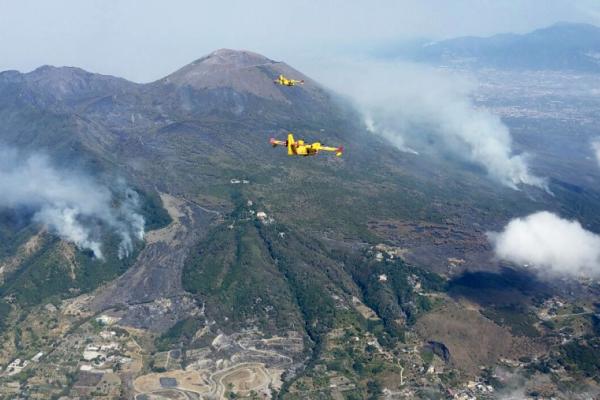 Aerial view of a mountainous landscape with 2 firefighter planes above it.